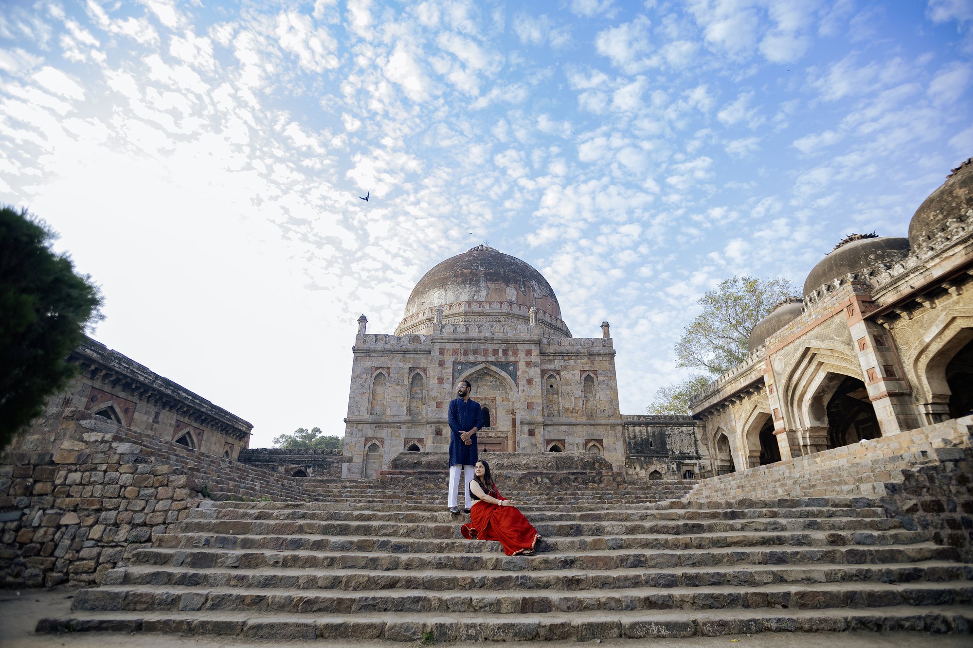 Beautiful pre-wedding moment of a couple in traditional attire sharing a loving glance while looking at the sky.